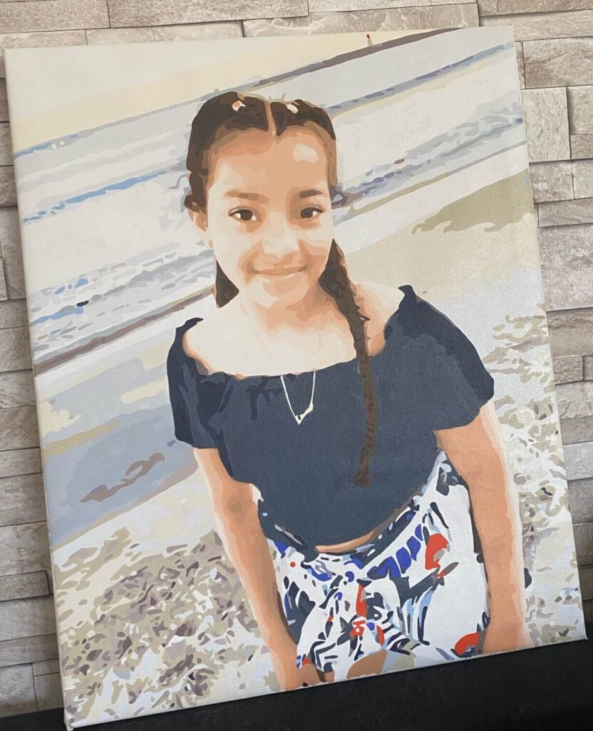 A photo of a girl with a genuine smile, representing a significant emotional moment. The simple background accentuates the focus on the kid's joyful expression, making it ideal for a custom paint by numbers project.