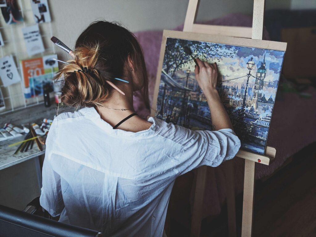 An artistic woman passionately painting on an easel, using vibrant strokes to bring her canvas to life.